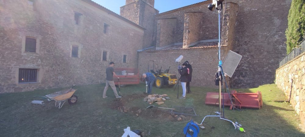 El equipo prepara focos y material en el patio de un edificio de piedra.