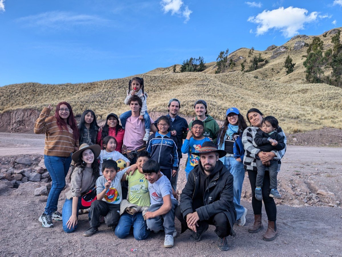 El equipo con un grupo de niños y familias en el altiplano andino, con las montañas al fondo.